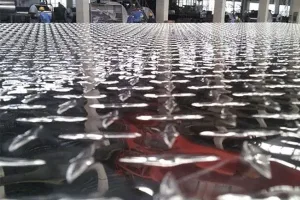 reflective checkered steel plate with raised tread pattern in a manufacturing facility