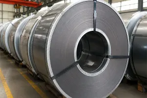Large rolls of cold rolled non-grain-oriented (CRNGO) silicon steel coils stored in a factory, used for manufacturing electric motor and generator cores.